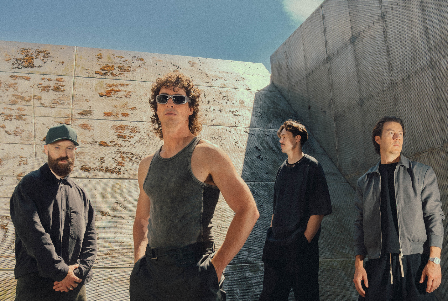 Band Don Broco with grey wall behind them and sky